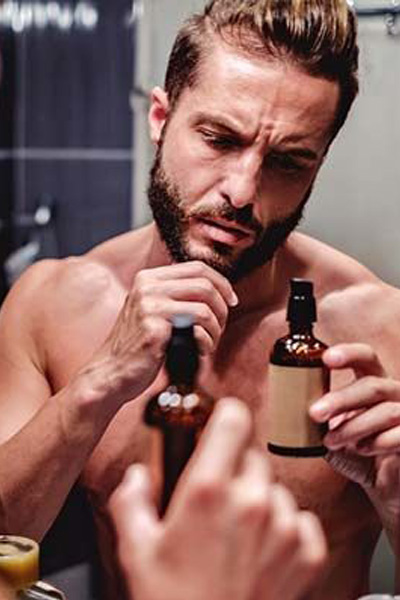 homme utilisant de l'huile de rasage pour préparer sa peau